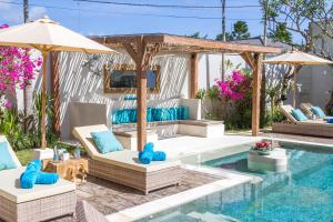 a pool with chairs and an umbrella next to a swimming pool at Villa Smilla in Seminyak