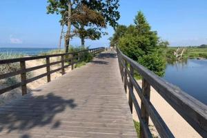 a wooden boardwalk next to the beach and water at Holiday home in Ustronie Morskie in a beautiful setting in Ustronie Morskie