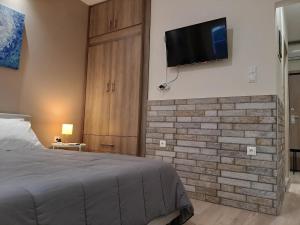 a bedroom with a bed and a tv on a brick wall at Byronico Acropolis Apartment by MPS in Athens +3 photos