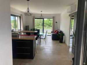 Gîte Ardoise في كاستيلنوداري: مطبخ وغرفة معيشة مع طاولة وكراسي