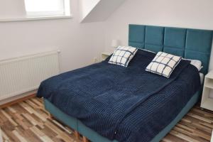 a bedroom with a blue bed with two pillows at Apartament Mąki Gram in Złocieniec