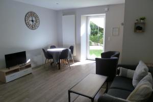 a living room with a table and a clock on the wall at Chez Berni in Millau