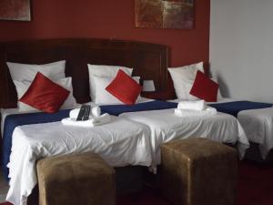 a hotel room with two beds with red and white pillows at Ehrlichpark Lodge self catering and spa in Bloemfontein
