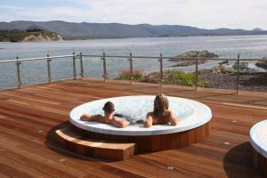 dos personas sentadas en una bañera de hidromasaje en una terraza en The Woodland Villas at Parknasilla Resort en Sneem