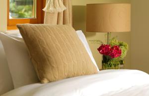 a pillow on top of a bed with a vase of roses at The Woodland Villas at Parknasilla Resort in Sneem