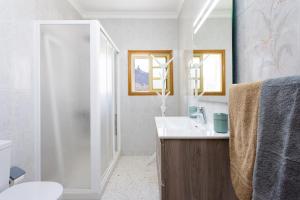 La salle de bains blanche est pourvue d'un lavabo et d'une douche. dans l'établissement Casa Maruca with Roque Nublo view, à Tejeda