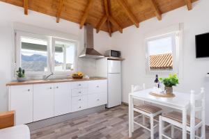 a kitchen with white cabinets and a white table at Casa Isabela with Roque Nublo view in Tejeda