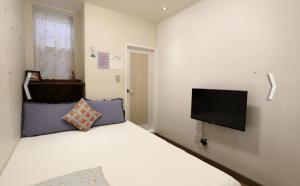 um quarto com uma cama branca e uma televisão de ecrã plano em Yujeong Guesthouse em Jeonju