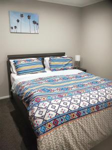 ein Bett mit einer bunten Decke in einem Schlafzimmer in der Unterkunft Trentham Gem in Upper Hutt