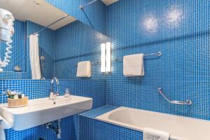 a blue tiled bathroom with a sink and a tub at Hotel König von Ungarn in Vienna