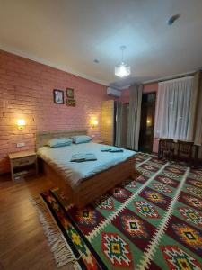 um quarto com uma cama grande e uma parede de tijolos em MUSAVVIR em Samarkand