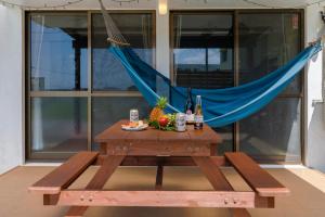a picnic table with a blue hammock on a patio at BANKSHI-SA in Motobu