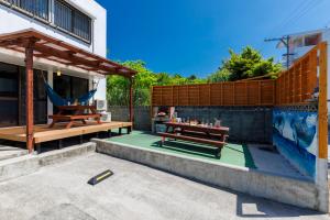 a patio with a table and a hammock next to a building at BANKSHI-SA in Motobu