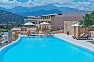 una piscina en un hotel con montañas en el fondo en Crete Golf Club Hotel, en Hersonissos