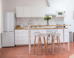 eine Küche mit weißen Schränken und einer Theke mit Stühlen in der Unterkunft Le Loft Saint Saëns in Marseille