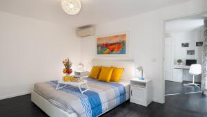 una camera da letto bianca con un letto con cuscini gialli di VILLA CRISTINA 3, Emma Villas a Marliana