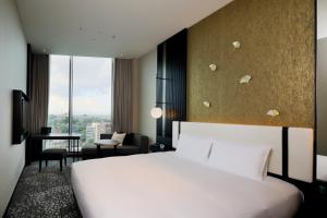 um quarto de hotel com uma cama branca e uma secretária em KOKO HOTEL Premier Kumamoto em Kumamoto