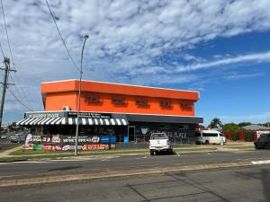 an orange building with a white van parked in front of it at Tomato Backpackers in Bundaberg