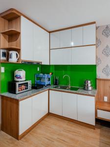 una cocina con armarios blancos y paredes verdes en Coco Homestay, en Phu Quoc