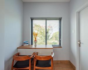 a dining room table with two chairs and a window at Coco Homestay in Phu Quoc