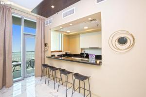 a kitchen with bar stools and a view of the ocean at bnbmehomes - High-floor Skyscraper - Sea View - 4801 in Dubai