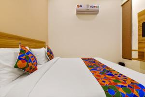 1 dormitorio con cama blanca y almohadas coloridas en FabHotel Prime Oxus, en Jaipur