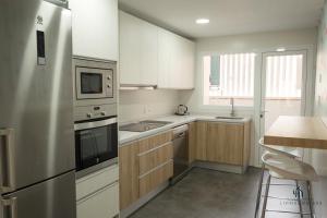 eine Küche mit weißen Schränken und einem Edelstahlkühlschrank in der Unterkunft Living4Malaga Arenal Superior Beach in Málaga