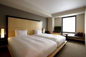 1 cama blanca grande en una habitación de hotel en KOKO HOTEL Premier Kanazawa Korinbo, en Kanazawa
