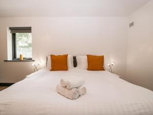 1 dormitorio con 1 cama blanca grande y toallas. en The Cottage, en Wimborne Minster