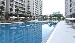 a swimming pool with chairs and umbrellas and buildings at Scenic valley Serviced Apartment in Ho Chi Minh City