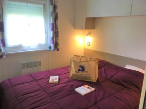 una bolsa y libros en una cama en una habitación en Camping et Gîte La Garenne de moncourt baie somme, en Rue