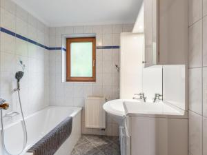 Baño blanco con bañera y lavamanos en Apartment Prieslern - BMG191 by Interhome, en Bramberg am Wildkogel