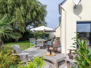 Un patio con una mesa y sillas y una sombrilla. en Holiday Home Ker Simor Ty Mer by Interhome, en Kerlouan
