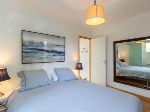 1 dormitorio con cama azul y espejo grande en Holiday Home Ker Simor Ty Mer by Interhome, en Kerlouan