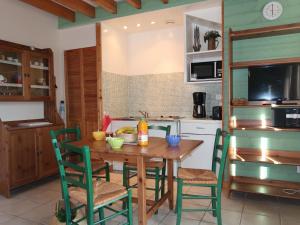 une cuisine avec une table en bois et des chaises vertes dans l'établissement Chalet Le Chalet - A, à Cancale