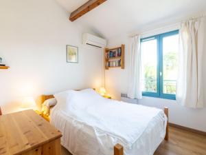 a bedroom with a bed and a table and a window at Holiday Home Les Olivades by Interhome in Plan-de-la-Tour +12 photos