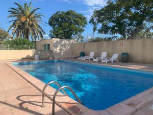 a swimming pool with chairs next to a wall at Apartment La Palme d'Or-5 by Interhome in Cap d'Agde