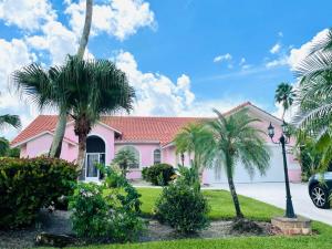 una casa rosa con palmeras delante en Villa Hibiscus by Interhome, en Bonita Springs