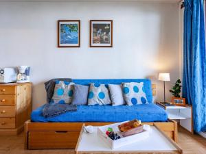 um sofá azul numa sala de estar com uma mesa em Apartment Lunik Orion-18 by Interhome em Le Corbier