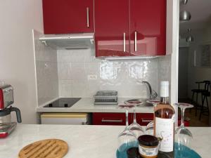 a kitchen with red cabinets and a counter with wine bottles at Apartment Le Viking by Interhome in La Grande Motte