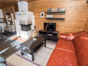 a living room with a leather couch and a television at Holiday Home Rintelä 5a by Interhome in Ruka