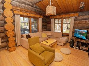 a living room with a couch and a tv in a log cabin at Holiday Home Villa vuosselinjärvi by Interhome in Ruka
