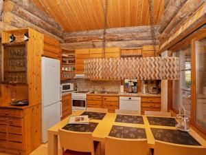a kitchen with wooden cabinets and a white refrigerator at Holiday Home Villa vuosselinjärvi by Interhome in Ruka