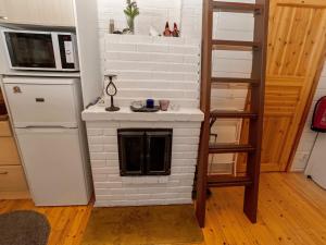 a kitchen with a fireplace with a refrigerator and a ladder at Holiday Home Kaukosaaren ahonrinne by Interhome in Ruka