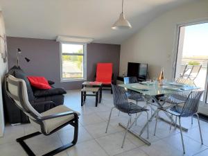 uma sala de estar com uma mesa e cadeiras e um sofá em Apartment Les Epinettes by Interhome em Saint-Gilles-Croix-de-Vie