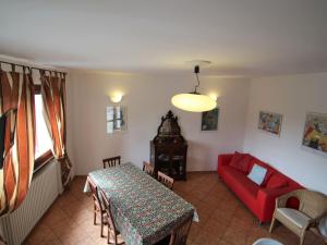 uma sala de estar com uma mesa e um sofá vermelho em Villa La Canonica-3 by Interhome em Brezzo