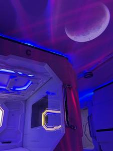 BMAX SPACEPODS في Pusok: غرفة بها أضواء أرجوانية وزرقاء على السقف