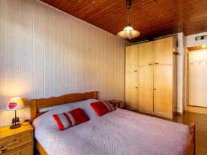 Apartment Super Tignes-2 by Interhome في تينيِ: غرفة نوم مع سرير مع وسادتين حمراء