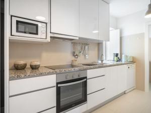a white kitchen with a stove and a microwave at Holiday Home De Pedral by Interhome in Castelo do Neiva