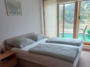 a bedroom with a bed and a large window at APARTMAN "CHARDAK" in Bjelašnica